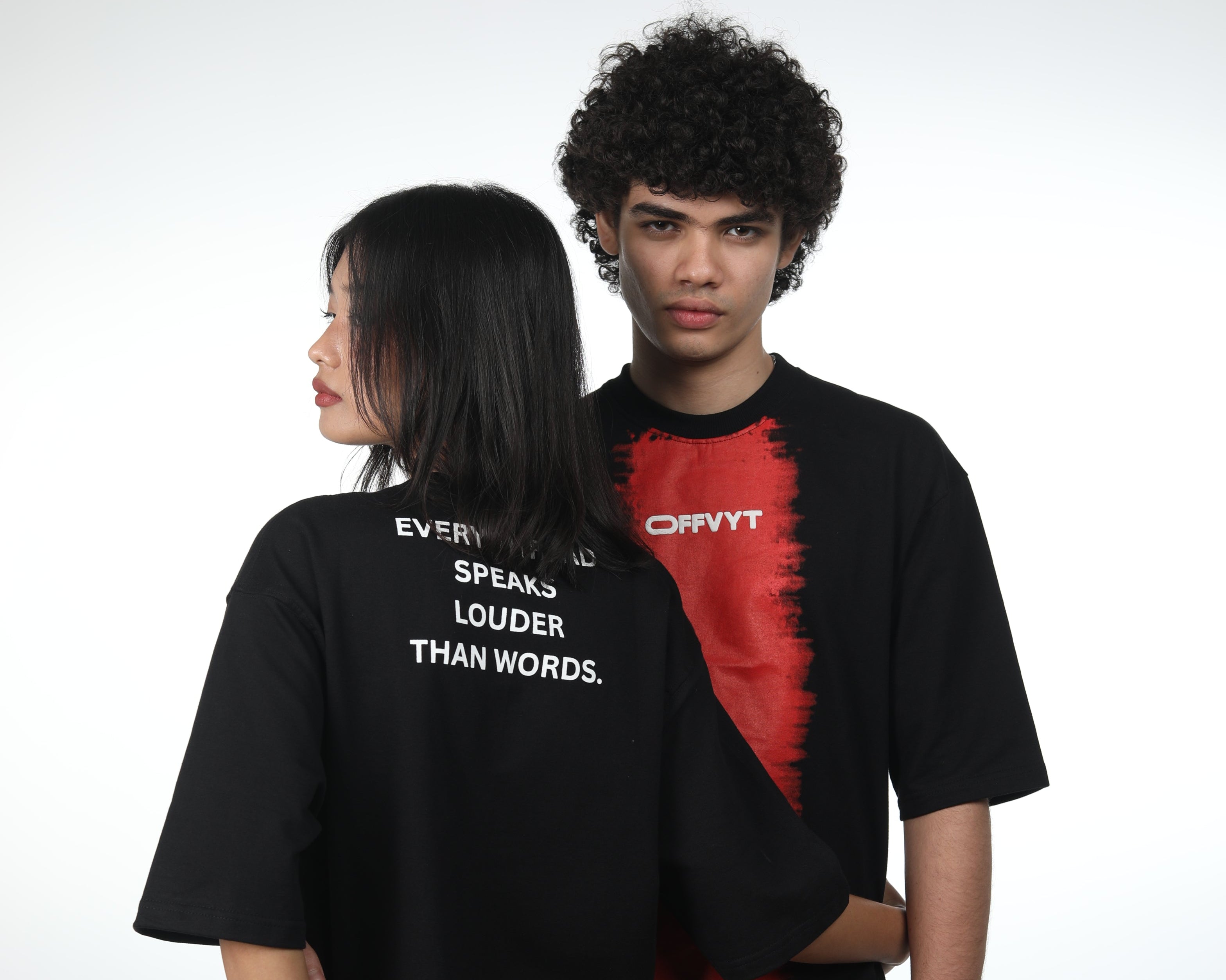 Two people wearing black t-shirts with visible branding against a white background